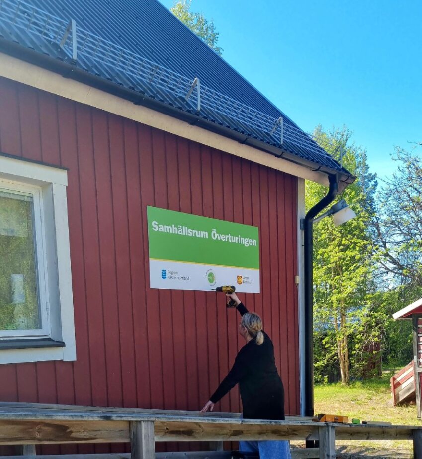 Jennie Näslund monterar upp en skylt på husfasaden.