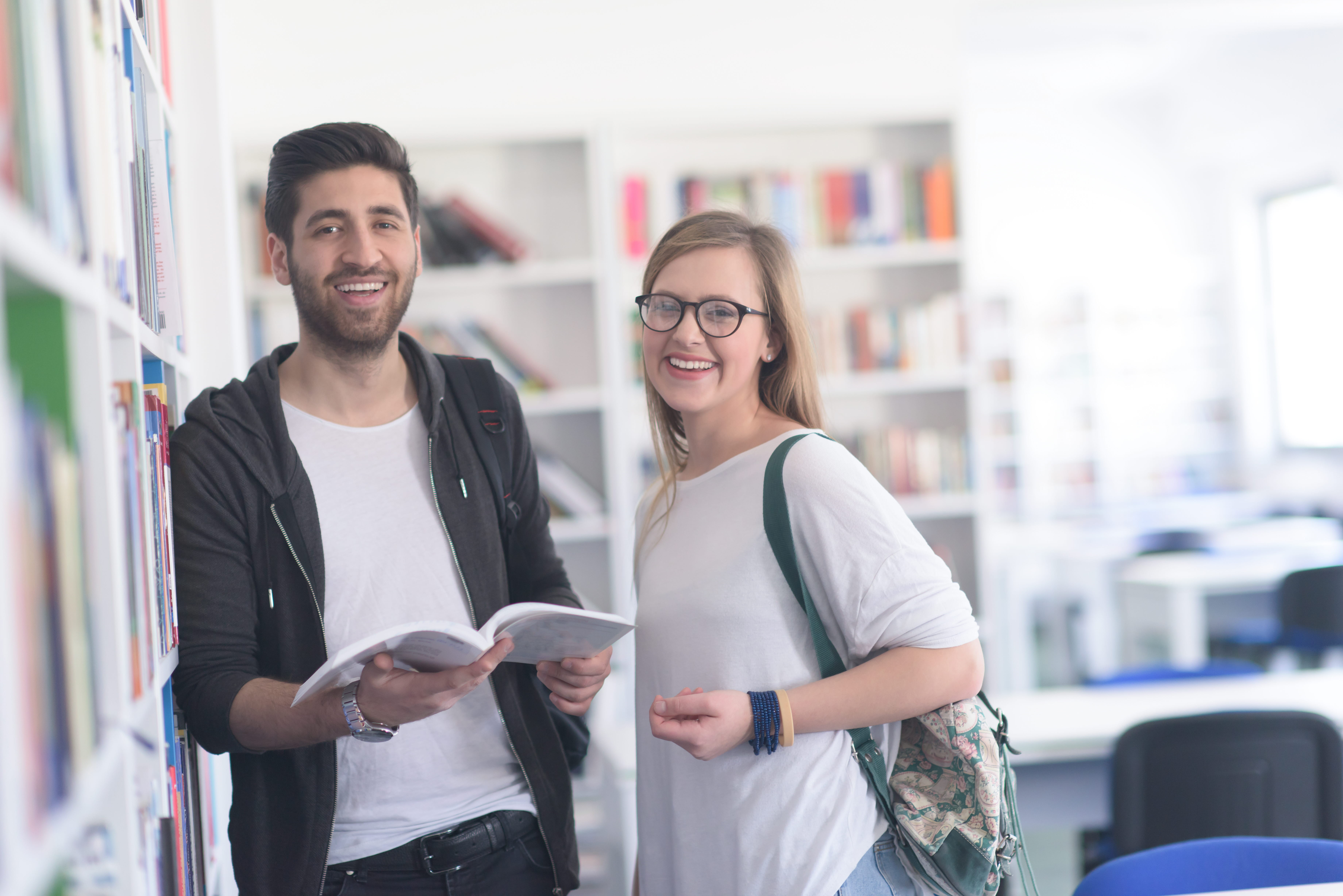 Två studenter som står vid en bokhylla. 