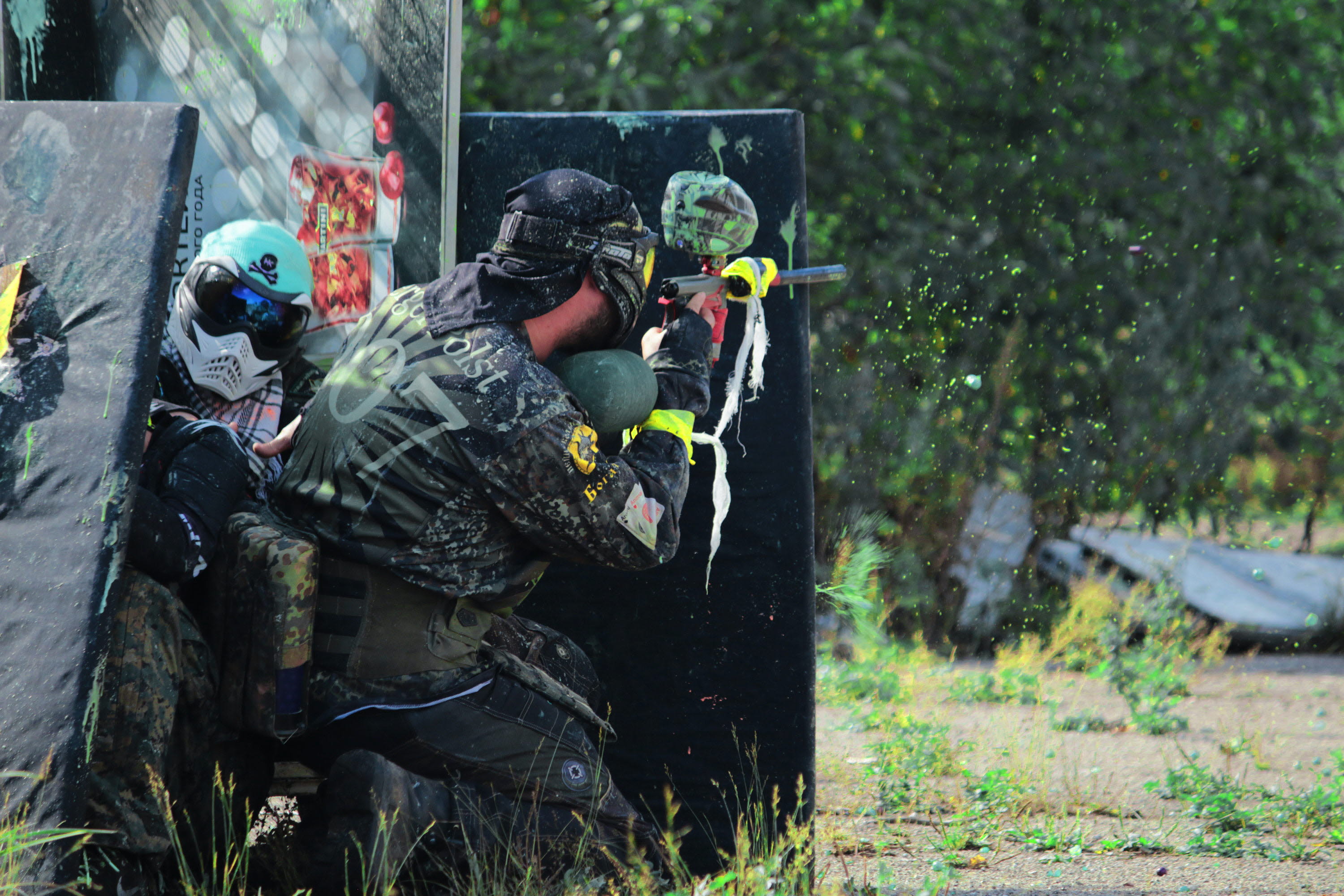 En person som spelar paintball står gömd bakom ett plank