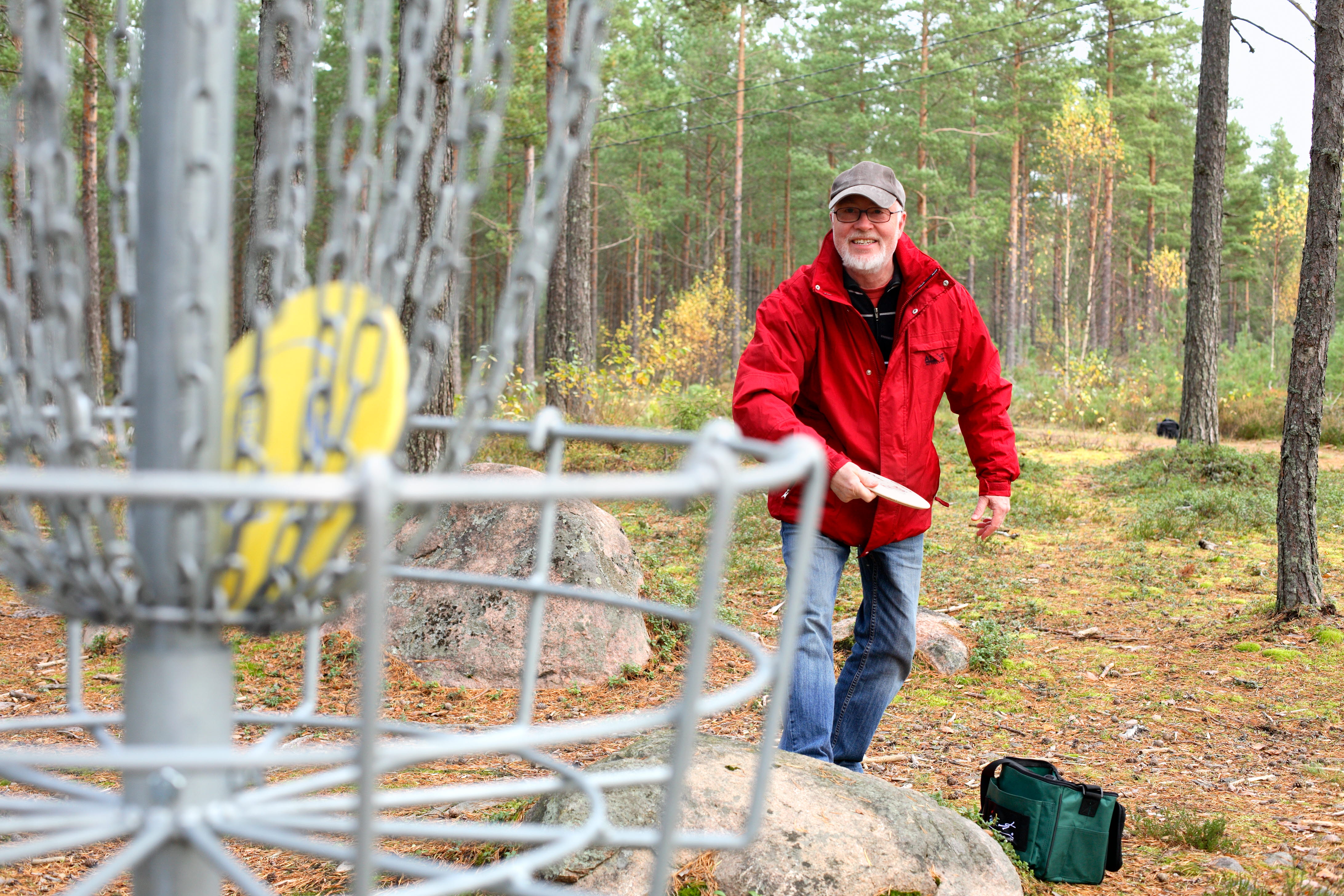 En man kastar en frisbee mot en korg i frisbeegolf