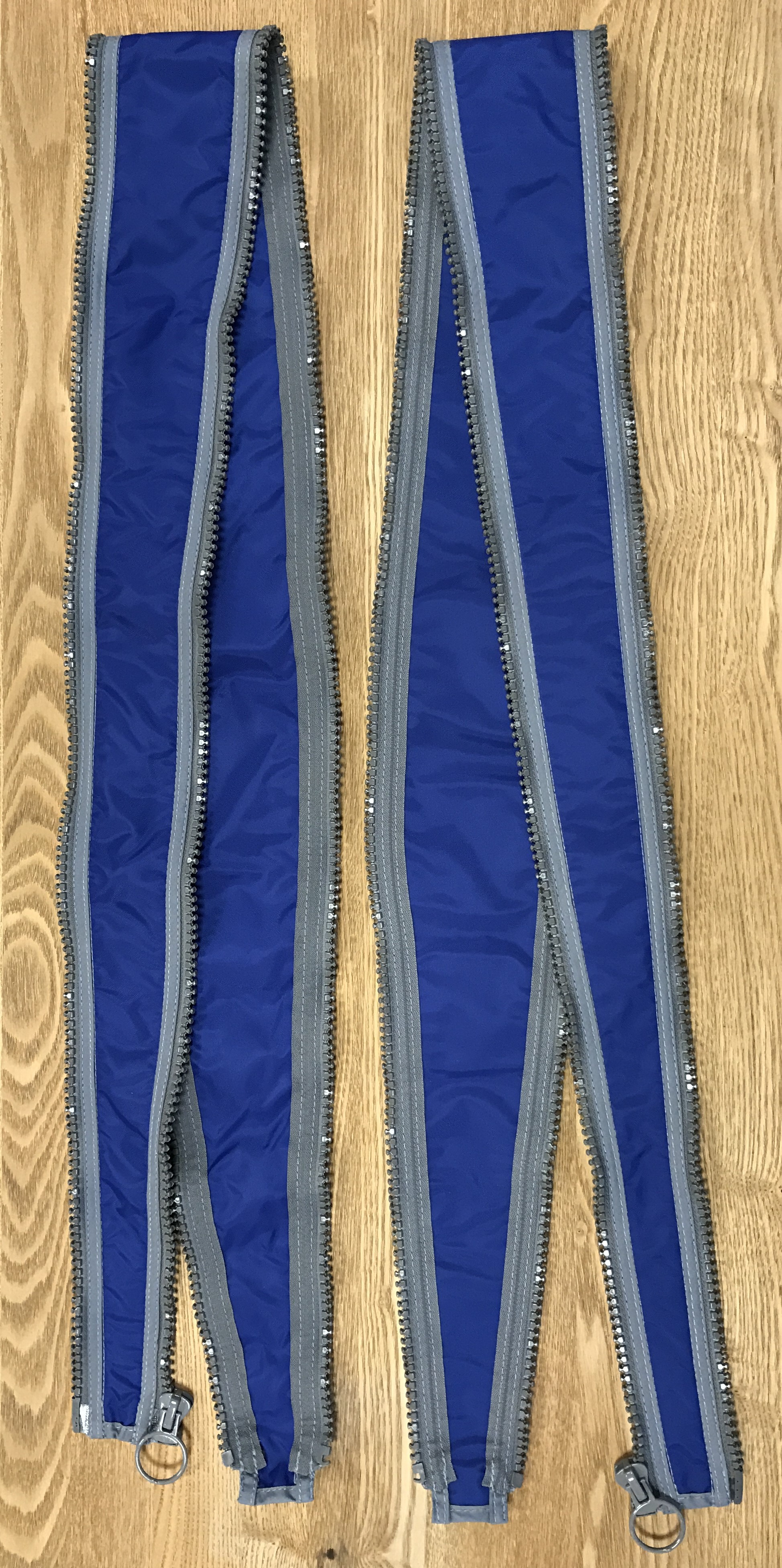 Två långsmala blå tygstycken med dragkedjor i sidorna.