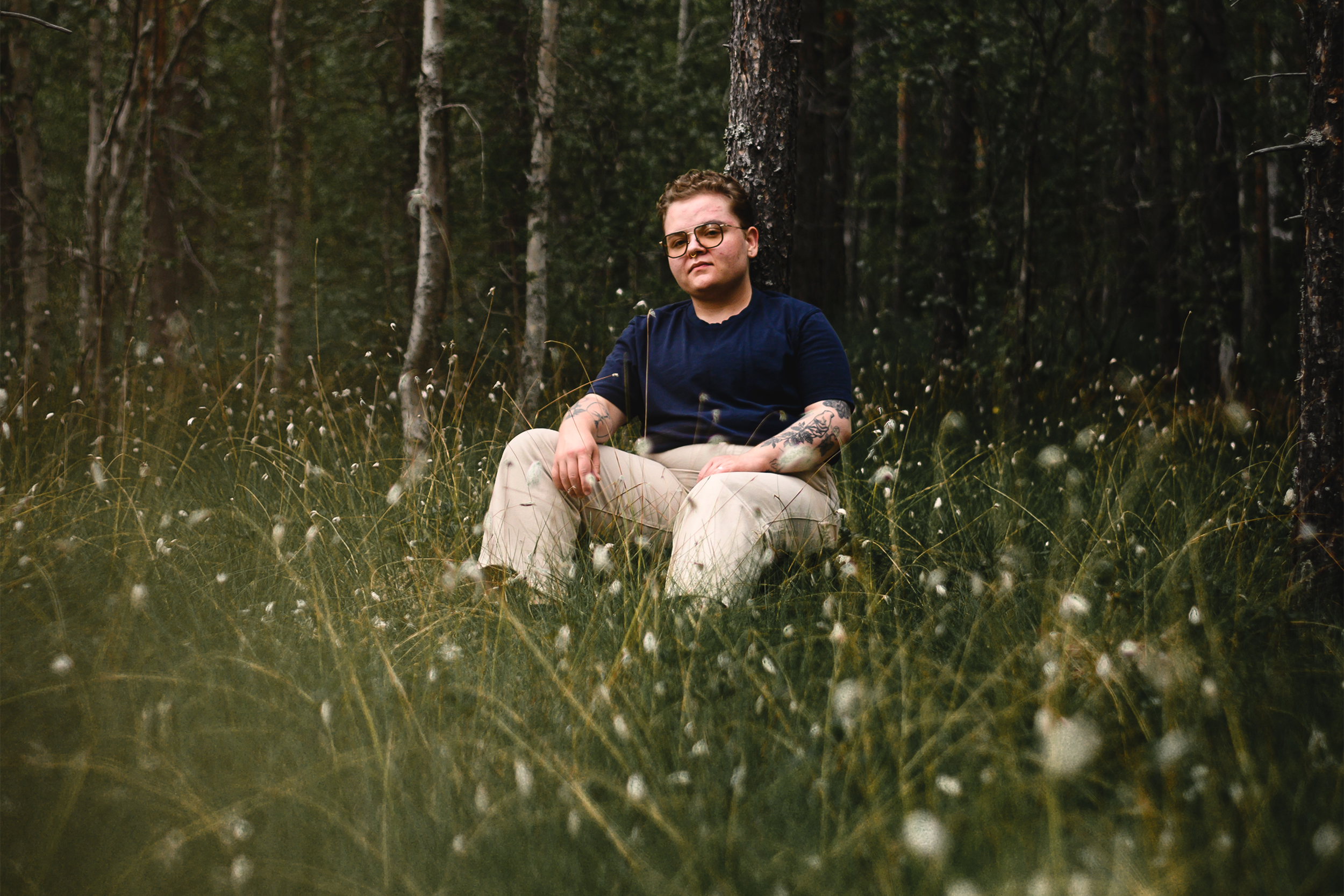 Lo Ragnar Lindström sitter lutad mot ett träd i en skogsglänta.