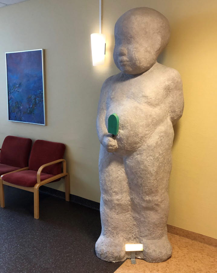 alt='Hög staty i ett rum föreställande ett litet barn med  en glass i handen'